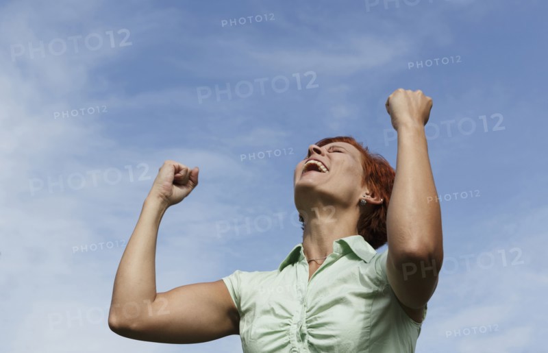 Caucasian woman cheering under blue sky
