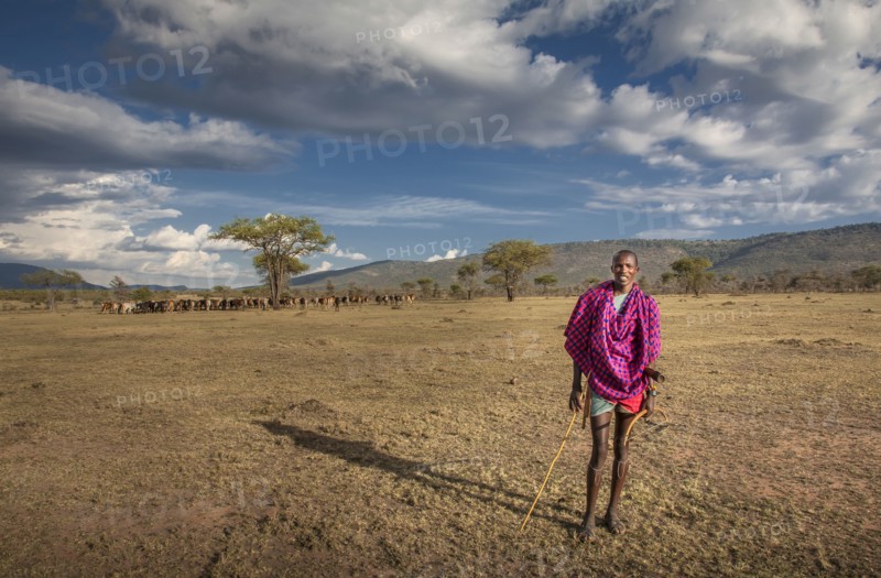 Black man in traditional clothing standing in remote field
