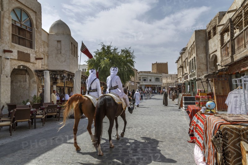 Men riding horses on Doha street