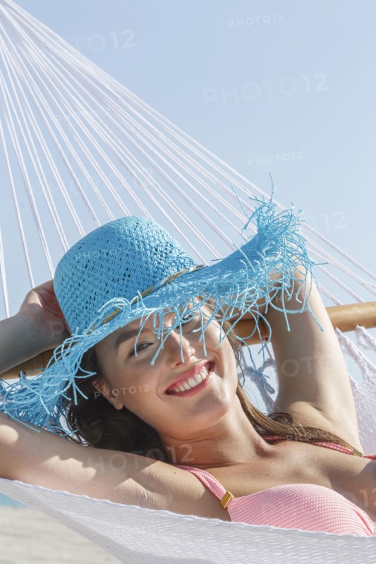 Caucasian woman wearing sun hat in hammock