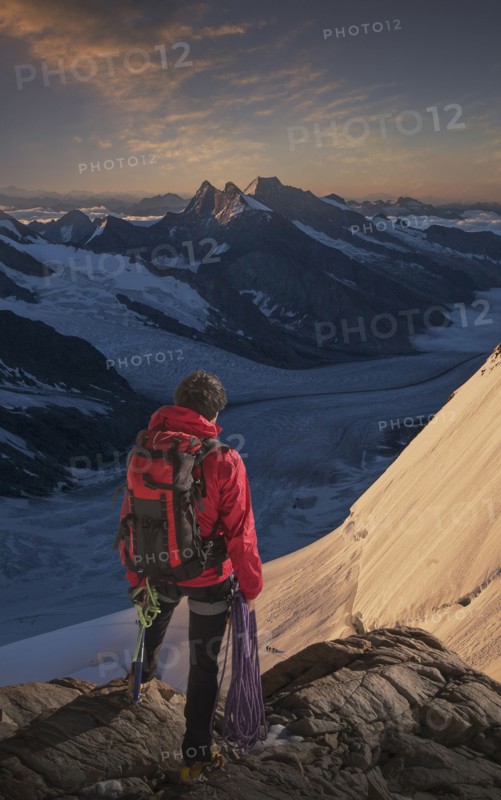 Caucasian man admiring mountain range holding climbing rope
