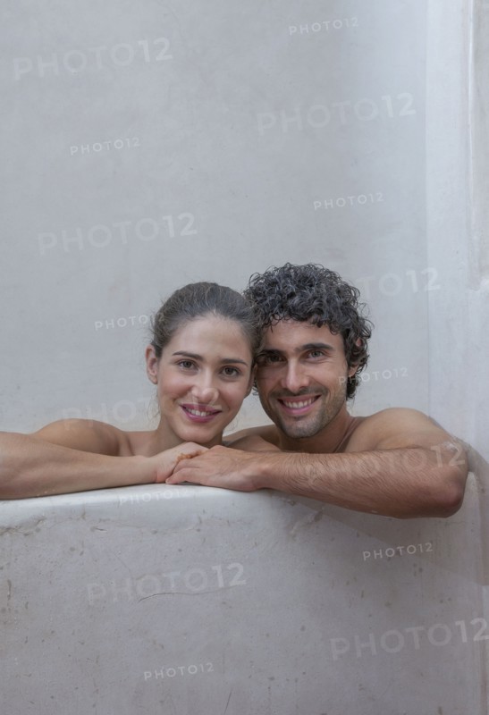 Smiling Caucasian couple relaxing in bathtub