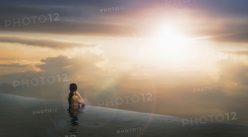 Chinese woman in infinity pool admiring sunset
