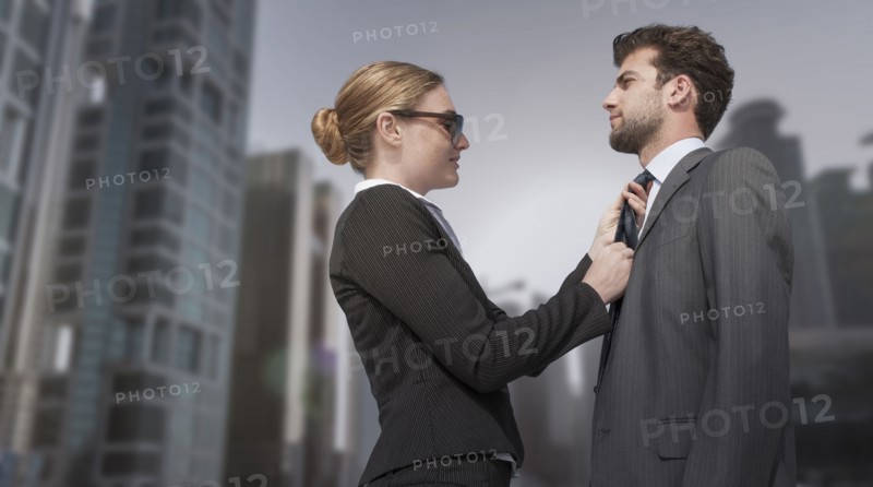 Caucasian businesswoman adjusting necktie for businessman