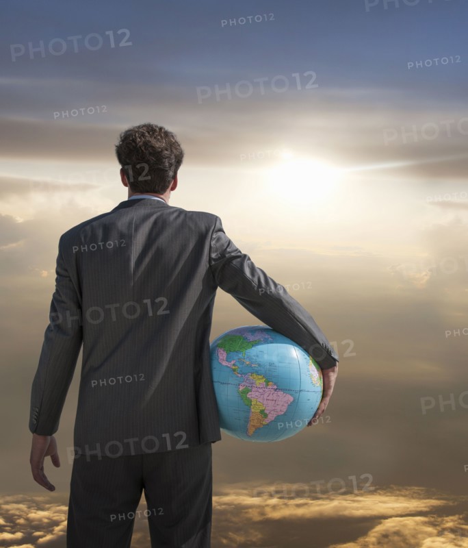 Caucasian businessman holding globe admiring sunset sky