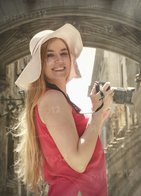 Portrait of smiling Caucasian woman holding camera in city