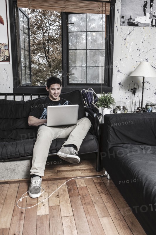 Mixed race man sitting on sofa with laptop