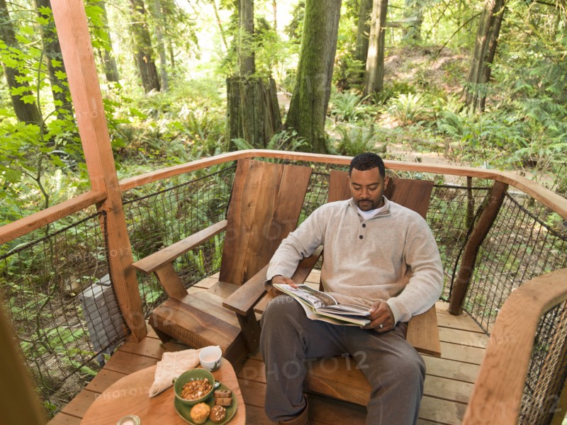 Mixed race man reading book on deck