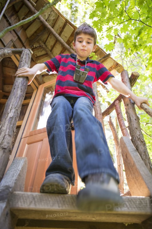 Caucasian boy climbing down from tree house