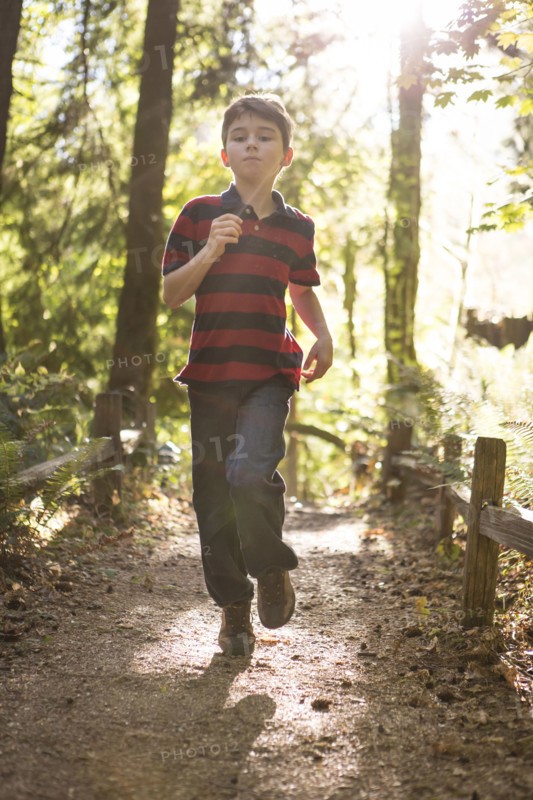 Caucasian boy running on path in forest