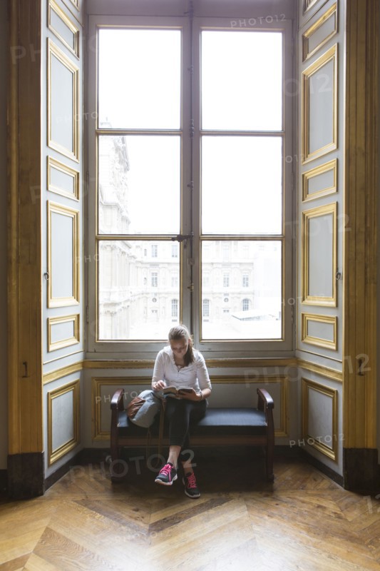Caucasian teenage girl studying in ornate window at Louvre Museum