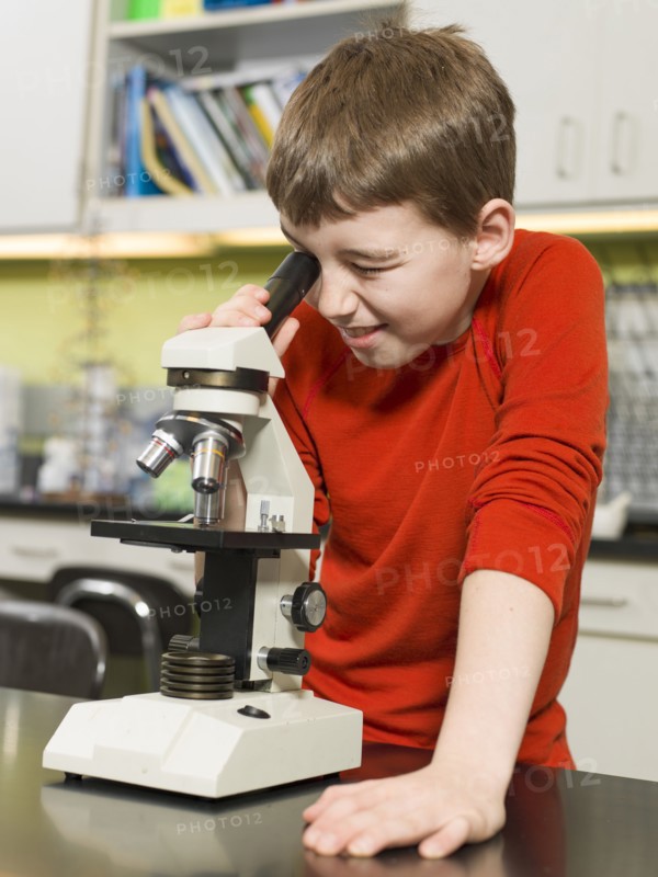 Caucasian boy using microscope in chemistry lab