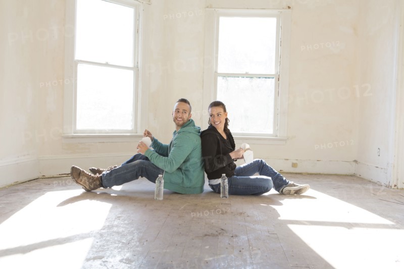 Mixed race couple sitting on floor of new home