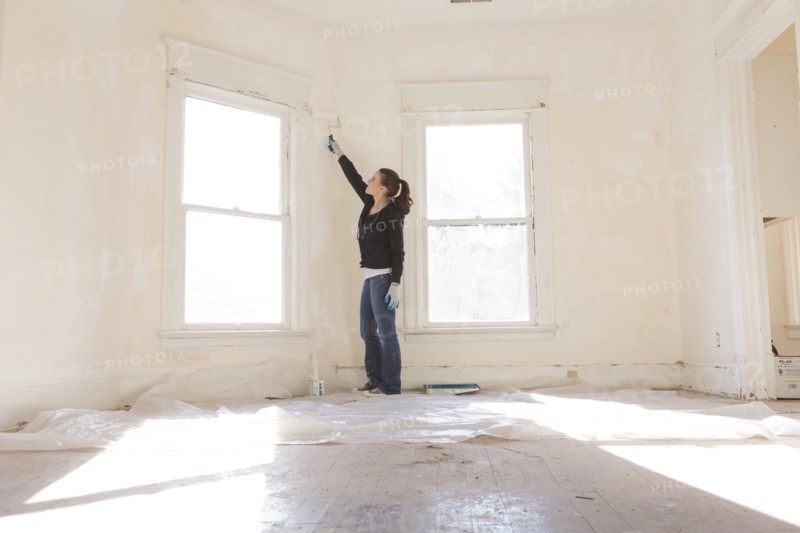 Mixed race woman painting walls of new home