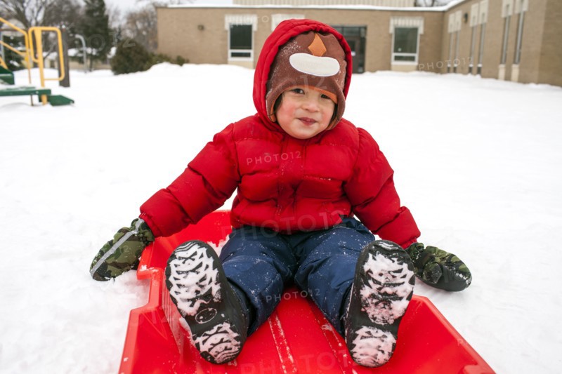 Mixed race boy sitting on sled in snow