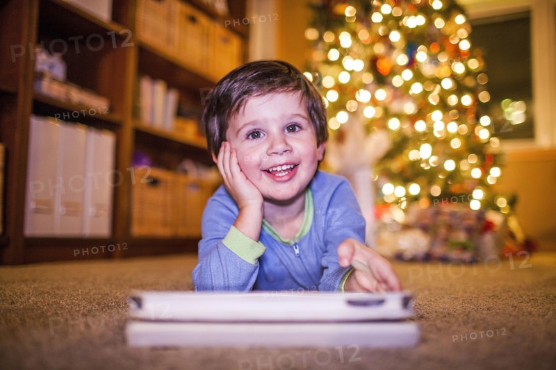 Caucasian boy using digital tablet by Christmas tree