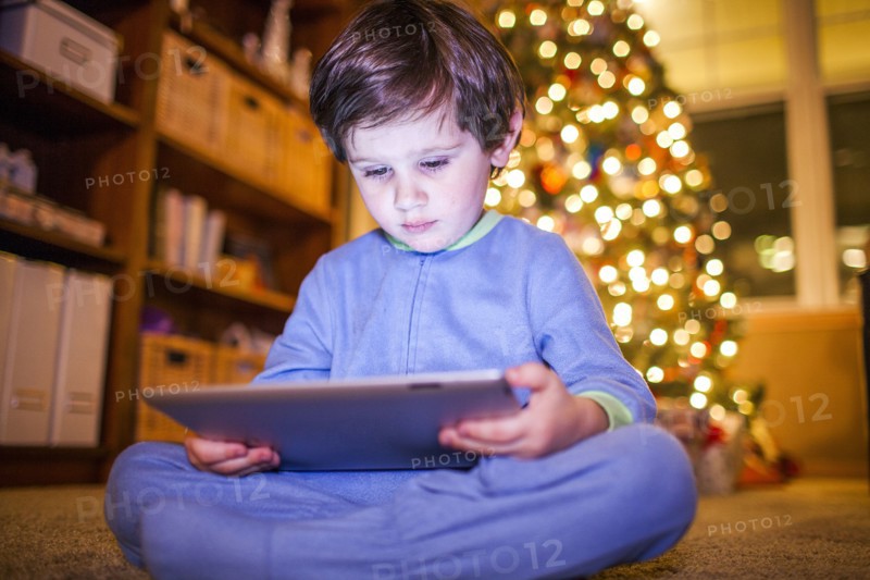 Caucasian boy using digital tablet by Christmas tree
