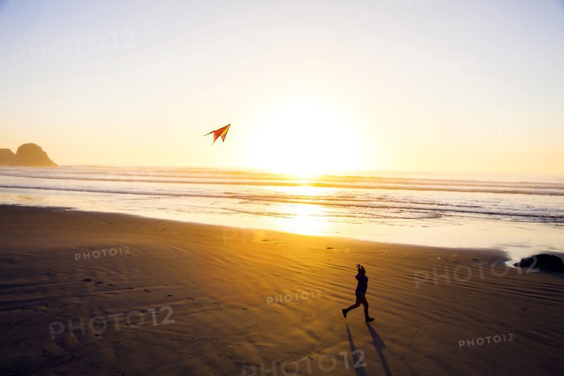 Caucasian woman flying kite on beach