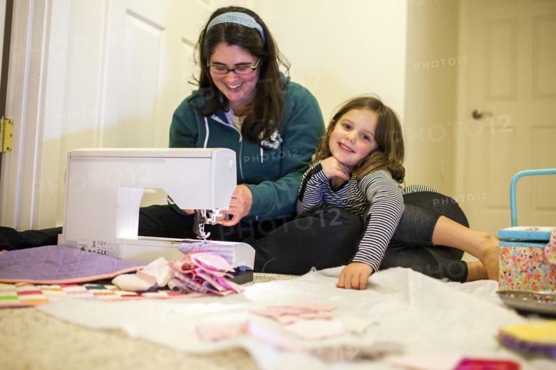 Caucasian mother teaching daughter to sew