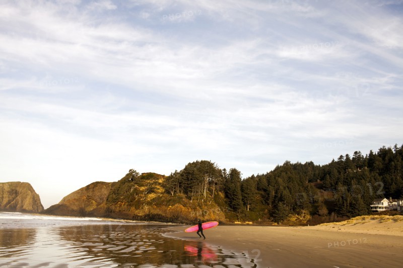 Surfer carrying board on beach