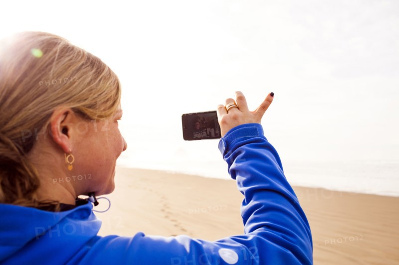 Caucasian woman taking pictures on beach