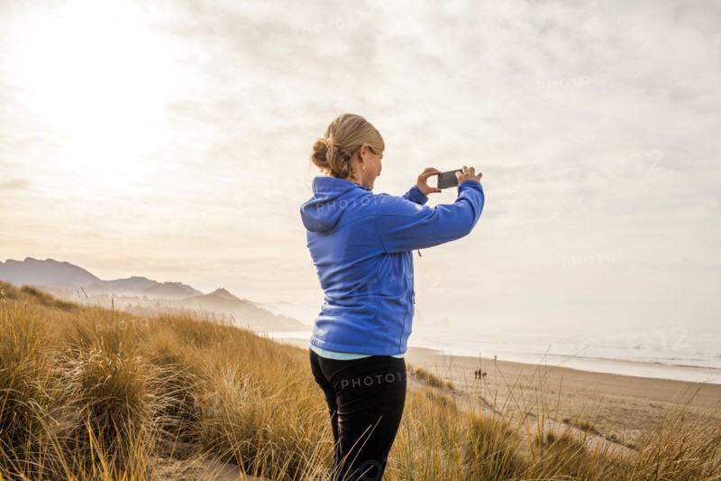 Caucasian woman taking pictures on beach