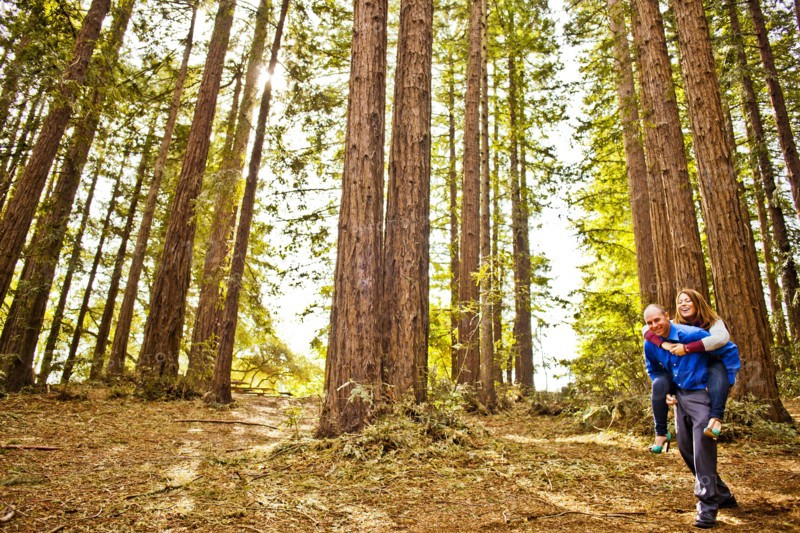 Hispanic man carrying girlfriend piggy back in forest