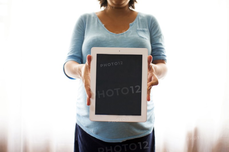 Pregnant Hispanic woman holding tablet computer