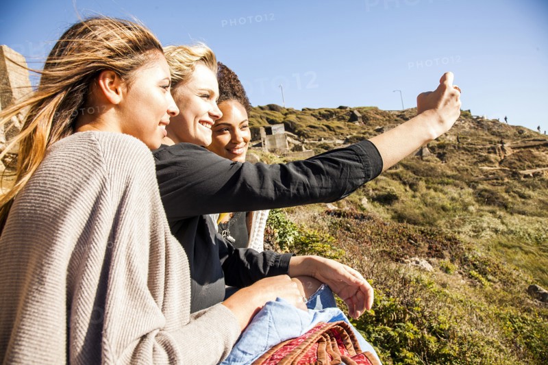 Women taking cell phone picture together on rural hillside