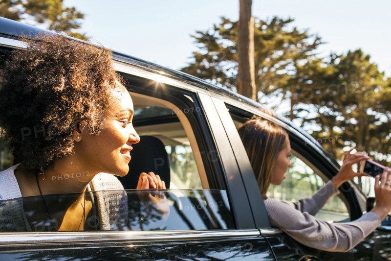 Women taking cell phone picture together in car
