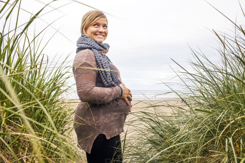 Caucasian pregnant woman holding her stomach on beach
