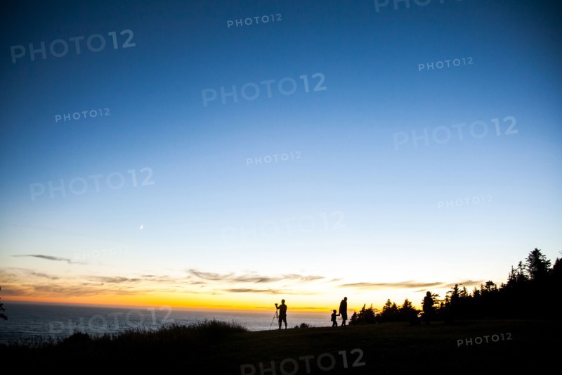 Silhouette of family on rural hillside at sunset