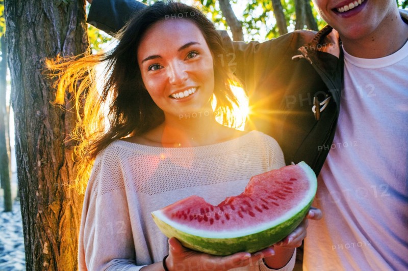 Caucasian couple eating watermelon at sunset