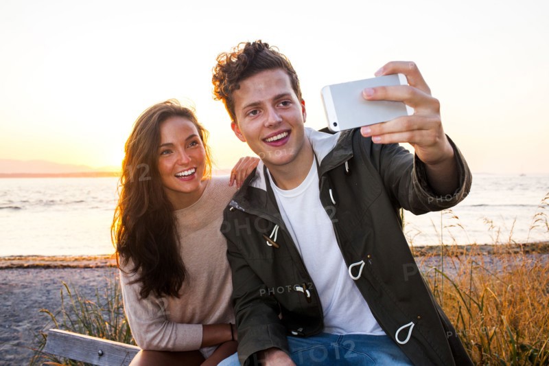 Caucasian couple taking selfie on beach