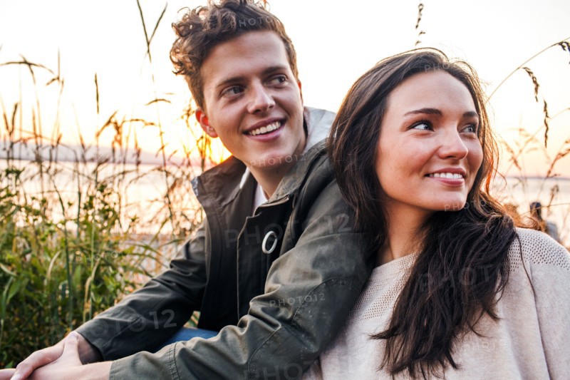 Caucasian couple sitting together on beach