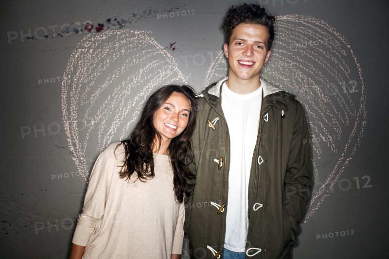 Caucasian couple smiling near chalk heart on wall