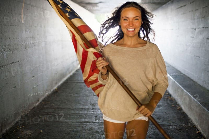 Caucasian woman carrying American flag in tunnel