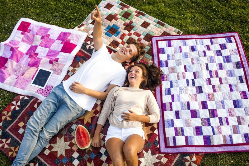 Caucasian couple relaxing on blankets in park