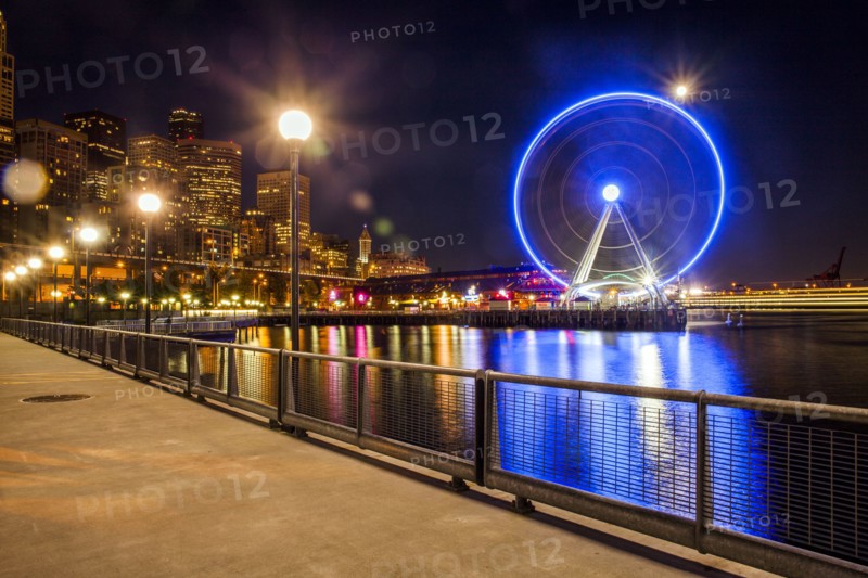 Illuminated ferris wheel on urban waterfront at night