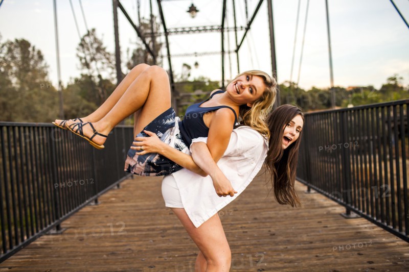 Caucasian teenage girls playing on wooden bridge