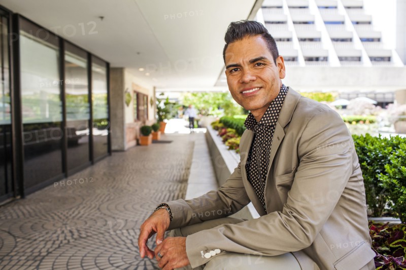Hispanic businessman leaning over outdoor bench