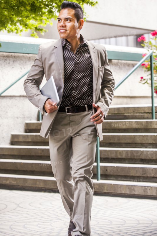 Hispanic businessman carrying digital tablet near staircase