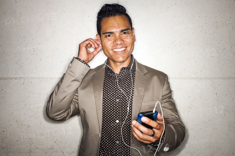 Hispanic businessman listening to earbuds with cell phone