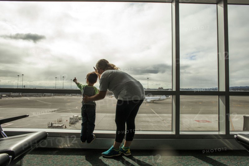 Mother and son looking out airport window