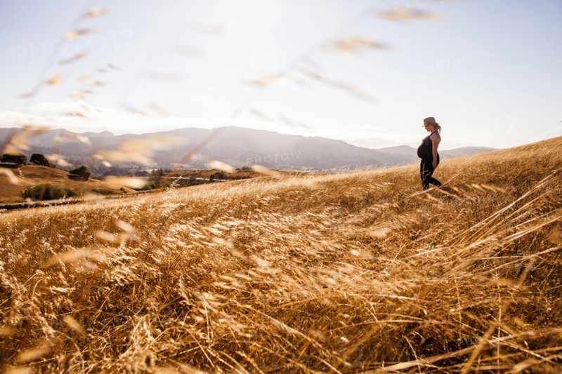 Pregnant Caucasian woman walking in rural meadow