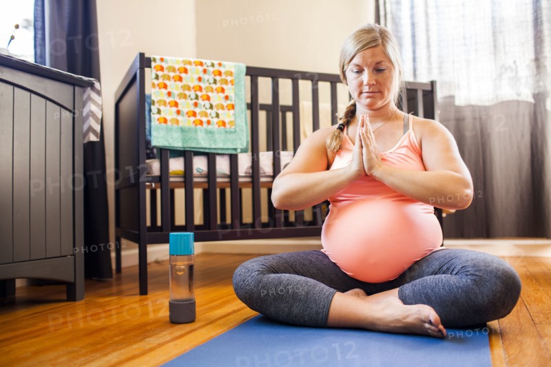 Pregnant Caucasian woman meditating in nursery