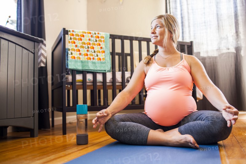 Pregnant Caucasian woman meditating in nursery