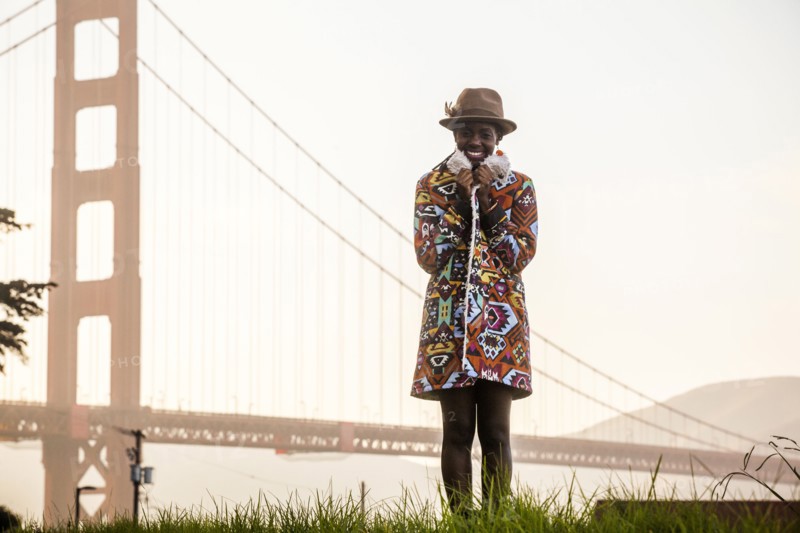 Black woman wearing colorful coat by Golden Gate Bridge