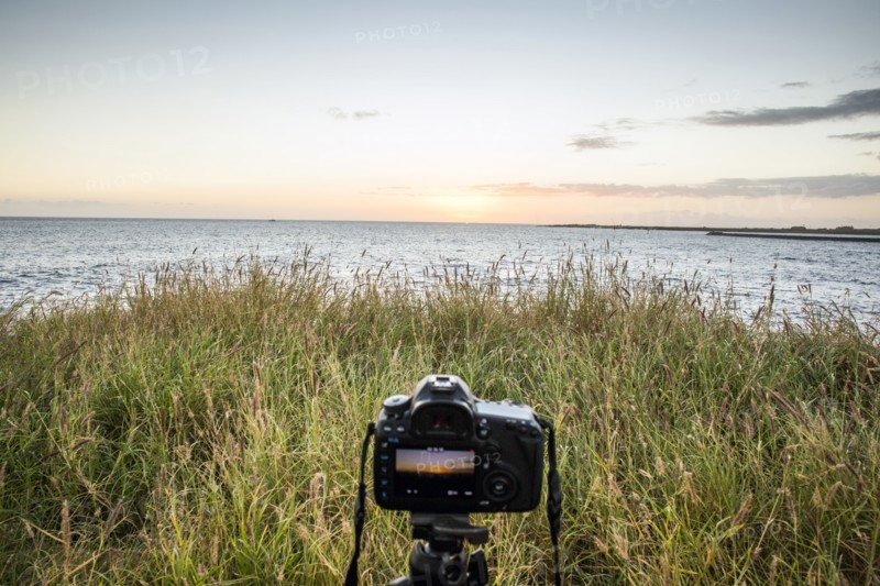 Close up of camera photographing sunset over ocean horizon