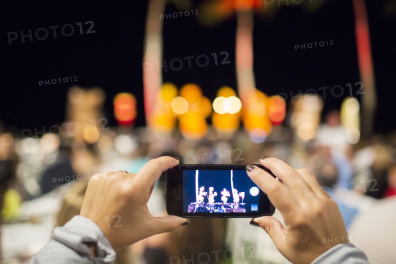 Close up of woman photographing hula dancers at luau